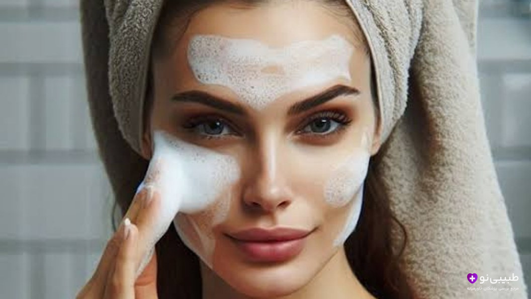 زن جوان در حال شستشوی صورت با فوم پاککننده و حوله روی سر